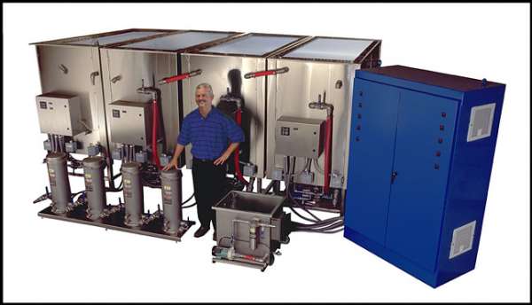man in blue shirt posing in front of custom ultrasonic cleaning system