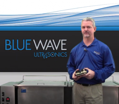 man wearing Blue Wave shirt in front of ultrasonic cleaning system